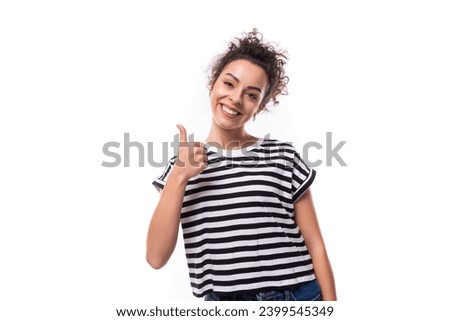 young cheerful curly brunette lady with black hair is dressed in a striped t-shirt on the background with copy space