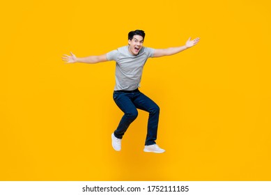 Young cheerful energetic handsome Asian man jumping with open hand gesture isolated on yellow studio background - Shutterstock ID 1752111185