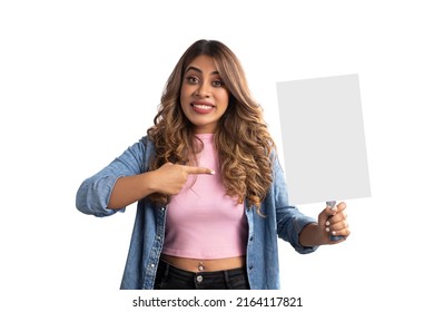 Young cheerful expressive smiling Indian Asian pretty happy brunette hair woman or female is holding and pointing a finger at a vertical rectangular shaped white colored banner, poster in her hand.