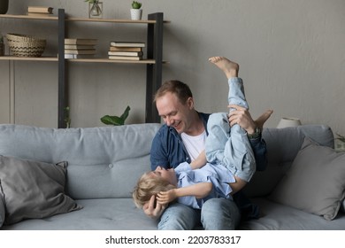 Young cheerful father play at home with adorable preschool son, vivacious active family look overjoyed spend weekend leisure, enjoy playtime together in coy living room. Bond, happy fatherhood concept