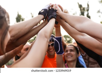 Young and cheerful friends gathered together. Team put hands up and show the unity. Ready to fight and protect all together. Friendship and love helps in sport. Morning training outdoor on the stadium