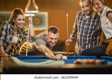 Young Cheerful Friends Are Playing Billiards In Bar After Work. A Couple That Wins Fame And The Losers Are In A Bad Mood.