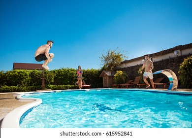 Young cheerful friends smiling, relaxing, jumping in swimming pool. - Powered by Shutterstock