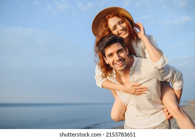 Young cheerful happy couple two friends family man woman in white clothes boyfriend give piggyback ride to joyful, girlfriend sit on back at sunrise over sea beach ocean outdoor seaside in summer day