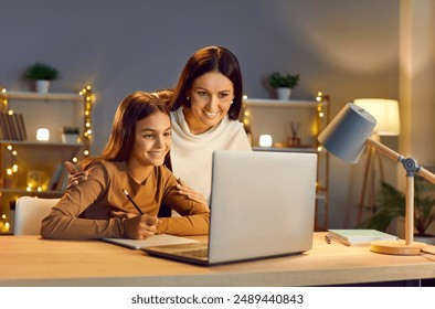 Young cheerful happy mother with her teen school girl daughter studying online class on laptop at home during remote lesson. Woman parent helping child with homework. Distance education. - Powered by Shutterstock