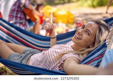 Young cheerful hipster woman taking selfie while laying in hammock and holding beer. Holiday, togetherness, fun, lifestyle concept. - Powered by Shutterstock