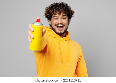 Young cheerful Indian man 20s he wearing casual yellow hoody hold in hand graffiti spray paint bottle point camera on you isolated on plain grey background studio portrait. People lifestyle portrait - Powered by Shutterstock