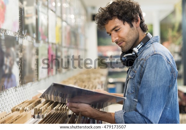 Young\
cheerful man browsing vinyl album in a record\
store