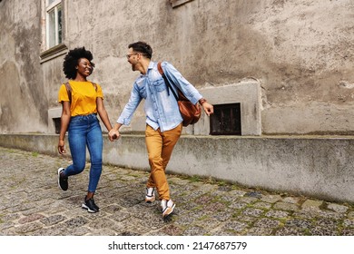 Young cheerful multicultural hipster couple walking in an old part of the town and holding hands. - Powered by Shutterstock