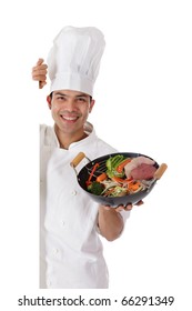 Young Cheerful Nepalese Man Chef Shows Oriental Food In Wok. Raw Meat On Side And Fresh Vegetables Mix. Studio Shot. White Background.