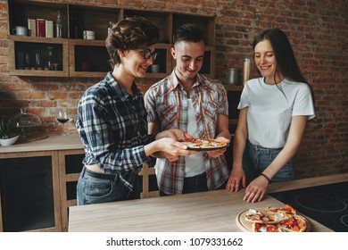 Young Cheerful Woman Bring Freshly Baked Homemade Pizza To Her Friends. Friendship, Sharing, Community, Togetherness, People And Food Concept