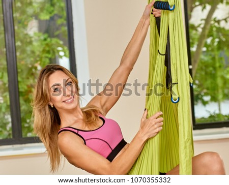Young cheerful woman doing antigravity yoga exercises