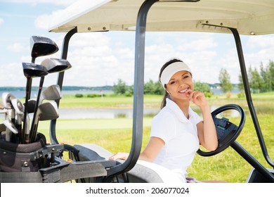 Young cheerful woman driving golf cart 