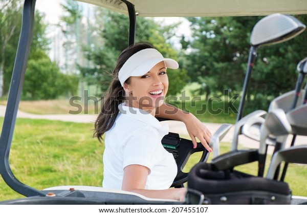 Young cheerful woman\
driving golf cart 
