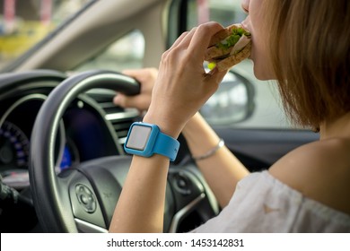 Young And Cheerful Woman Eating Healthy Sandwich With Salad Homemade While Driving Car In The City.