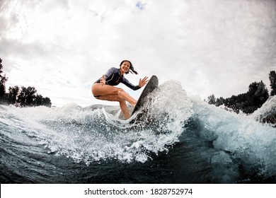 Young Cheerful Woman Is Engaged In Wake Surfing And Lot Of Water Splashes Around Her