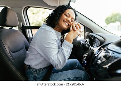 Young and cheerful woman enjoying new car hugging steering wheel sitting inside. Woman driving a new car. - Powered by Shutterstock