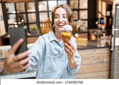 Young And Cheerful Woman Making Selfie Photo With Yummy Ice Cream In Waffle Cone, Having Fun In The Shop Or Cafe