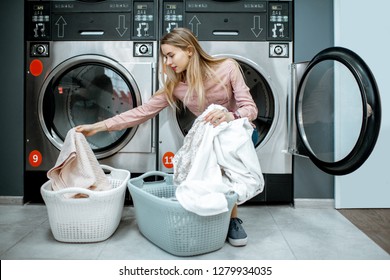 Young and cheerful woman sorting clothes sitting on the dryer machine in the laundry - Powered by Shutterstock