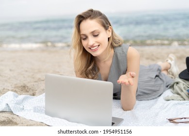 Young Cheerful Woman Working At The Laptop Computer With A Smile Lying At The Beach, Talking On Zoom Face Time Call 