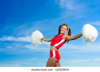 Young Cheerleader In Red Costume With Pampon Against Blue Sky