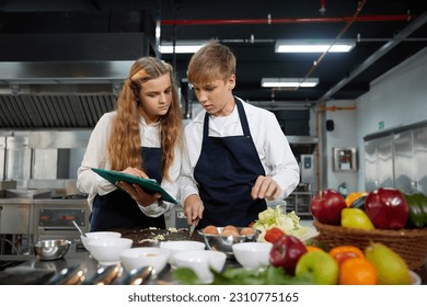 young chef cooking some food and preparing vegetable salad in the kitchen - Powered by Shutterstock