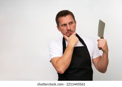 Young Chef With Cutting Knife. Butcher In A Black Apron Holding Kitchen Cleaver