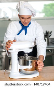 Young Chef Using Electric Egg Beater In Kitchen