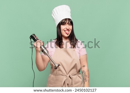 young chef woman with cheerful, carefree, rebellious attitude, joking and sticking tongue out, having fun