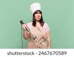 young chef woman feeling disgusted and irritated, sticking tongue out, disliking something nasty and yucky