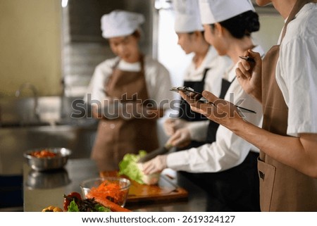 Young chefs documenting cooking steps while learning vegetable cutting skills in a kitchen