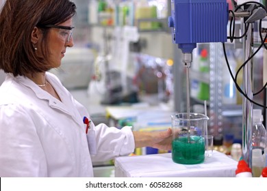 A young chemical engineer working at the chemistry laboratory. Laboratory Stirrer/Mixer. Chemist Working with Lab Mixer and Mixing Chemicals in an Experiment.