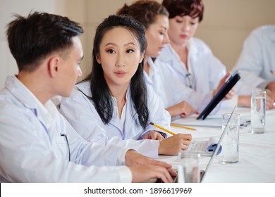 Young Chiense Female Scientist Talking To Colleague At Meeting Devoted To New Research