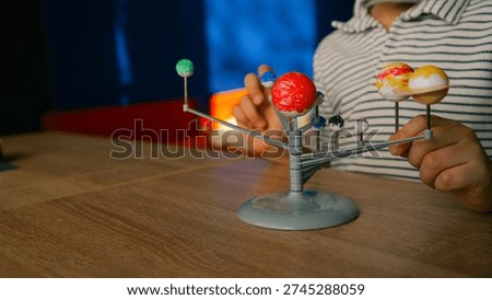 A young child is engaged in learning by manipulating a model of the solar system, featuring planets of various colors and sizes