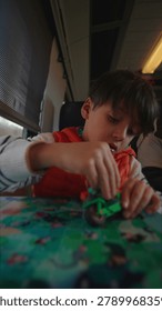 Young child focused on assembling colorful blocks while riding railway carriage, candid travel lifestyle scene reflecting creativity, independence and calm commute