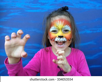 Young Child (girl Age 5-6) With Lion Face Painting Roaring Like A Lion On Halloween Purim Carnival Holiday.  Real People. Copy Space