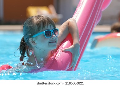 Young Child Girl Falling In Water From Inflatable Air Mattress In Swimming Pool While Swinnimg During Tropical Vacations. Safety Of Aquatic Activities Concept