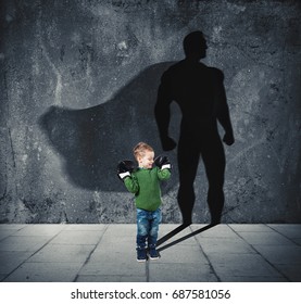 Young Child With His Shadow Of Super Hero On The Wall.