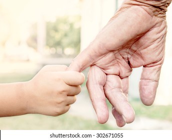 Young child holding her grandparent for the hand,selective focus 
