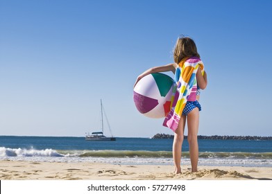 Young Child Holding Towel And Beach Ball At The Beach.