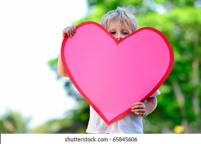 Young Child Holds A Big Pink Paper Heart