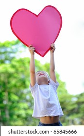 Young Child Holds A Big Pink Paper Heart