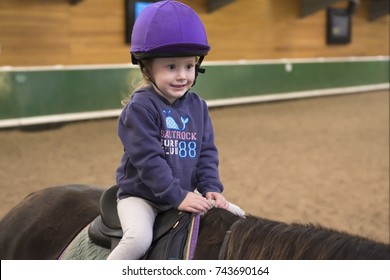 Young Child Horse Riding Lesson With Instruction At Equestrian Centre 