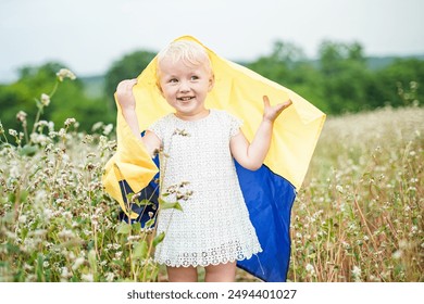 A young child joyfully waves the Ukrainian flag, celebrating Flag Day and Independence Day in a beautiful field of flowers. - Powered by Shutterstock