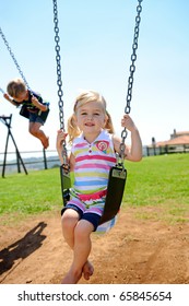Young Child On Swing In Playground Outdoors