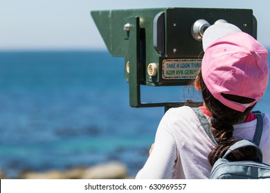 Young Child With A Peak Cap And Backpack On Vacation Looking Out To See The Ocean Horizon Through A Viewfinder
