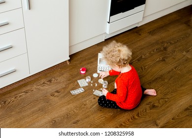 Young Child Play Alone With Pills Tablets On Home Kitchen Floor. Keep Away From Children Reach Concept. No Medicine Cabinet.