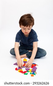 Young Child Playing And Learning To Do Math With With Deci Pattern Blocks Against White Background In Studio