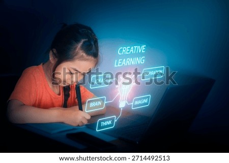 A young child sits at a table using a laptop in a low-light room. Ideas and concepts about creative learning appear around the child as they focus on writing.