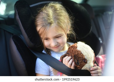 Young Child Sitting In The Back Of A Car In A Car Seat